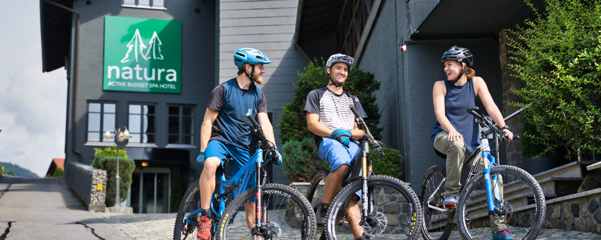 Drei Mountainbiker in Freizeitkleidung erkunden die Umgebung des natura Hotels im Bayerischen Wald.